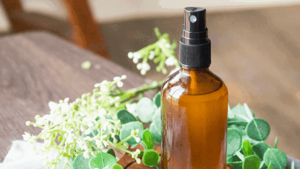natural DIY hand sanitizer spray bottle with essential oils vitamin E and witch hazel on rustic wood surface