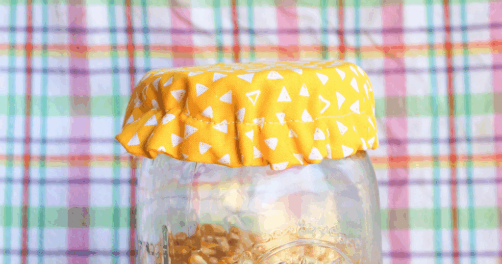 Detail shot of the yellow and white fabric pattern on a finished jar lid cover.