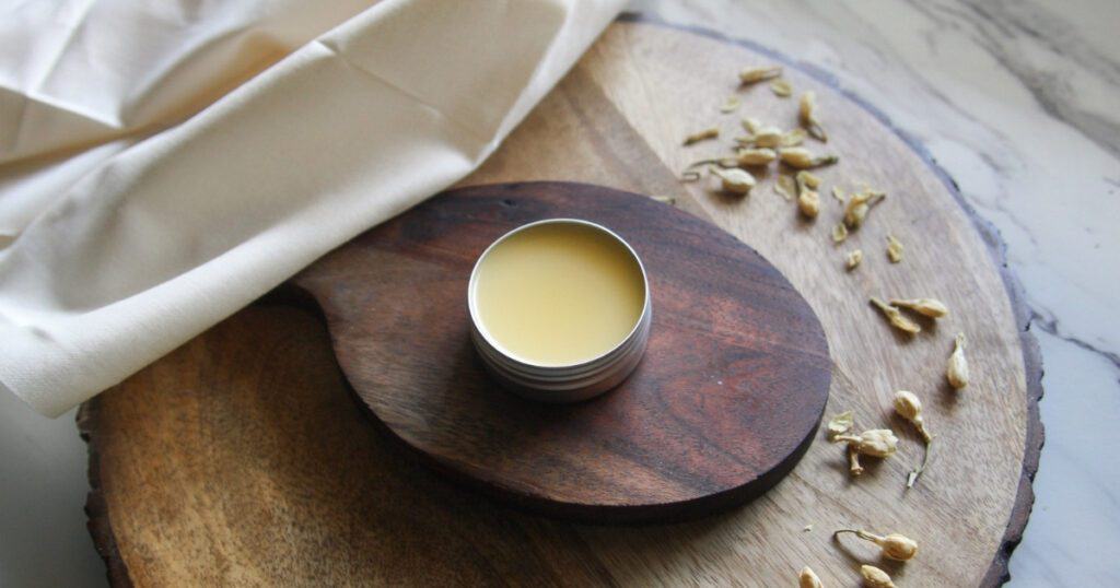 Glossy surface of a homemade tallow lip balm in a small silver tin.