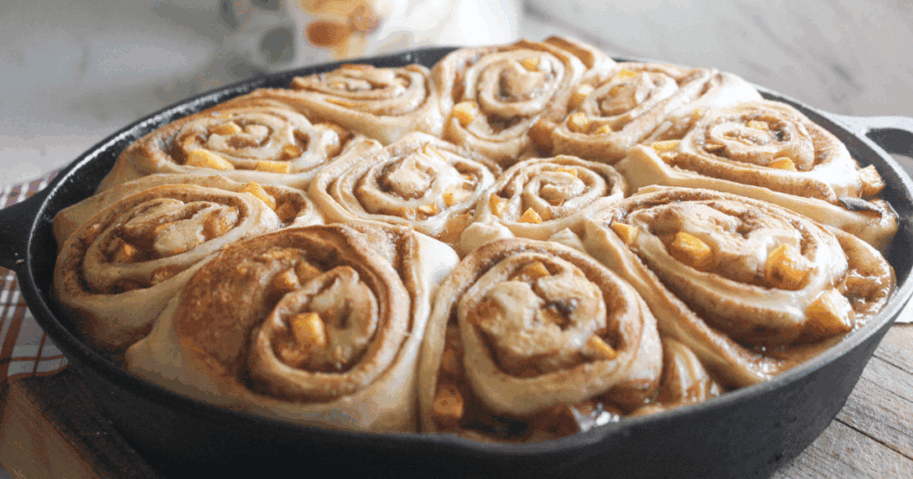 Golden brown peach cinnamon rolls without icing, still warm in a skillet.
