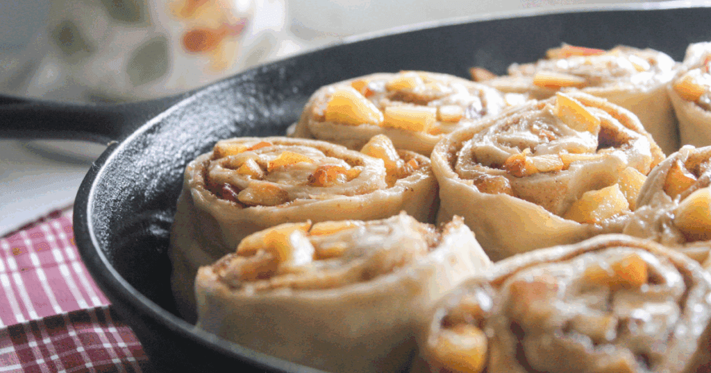 Peach cinnamon rolls arranged in a cast iron skillet before baking.