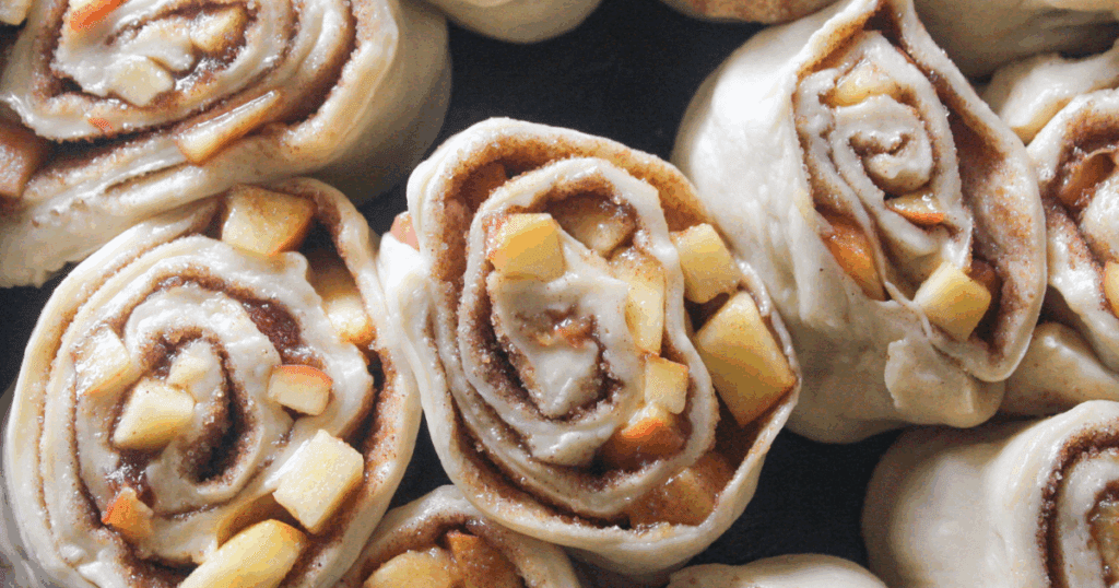 Close view of unbaked cinnamon rolls filled with diced peaches.