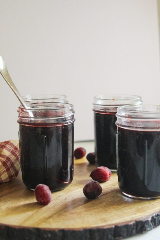 Four mason jars of cherry jam cooling after canning