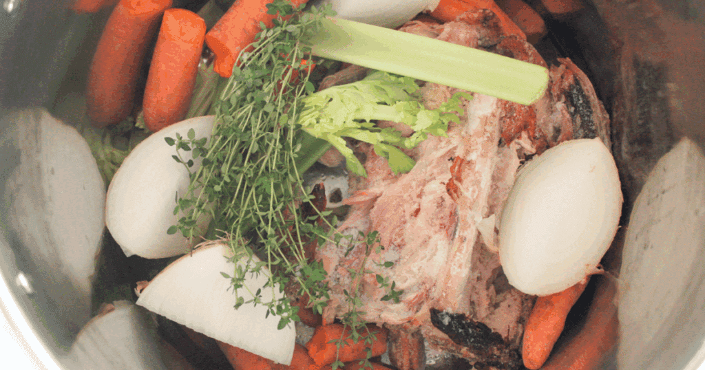 Chicken carcass, carrots, celery, onion, and thyme in a stockpot ready to simmer for homemade bone broth.