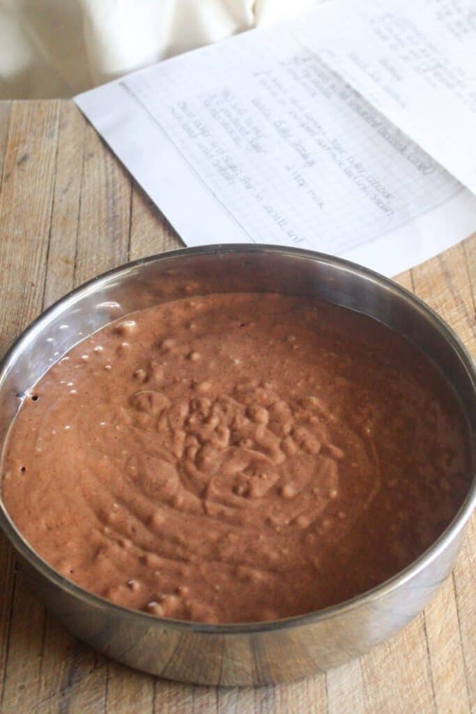 Chocolate cake batter spread evenly in a round cake tin, ready for the oven.