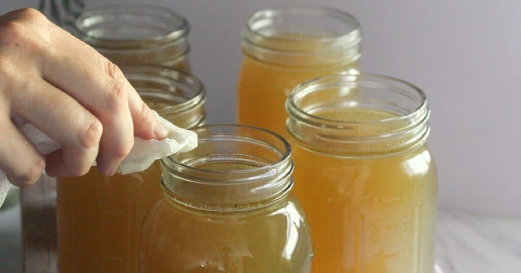 Wiping the rim of a mason jar with vinegar before pressure canning bone broth.