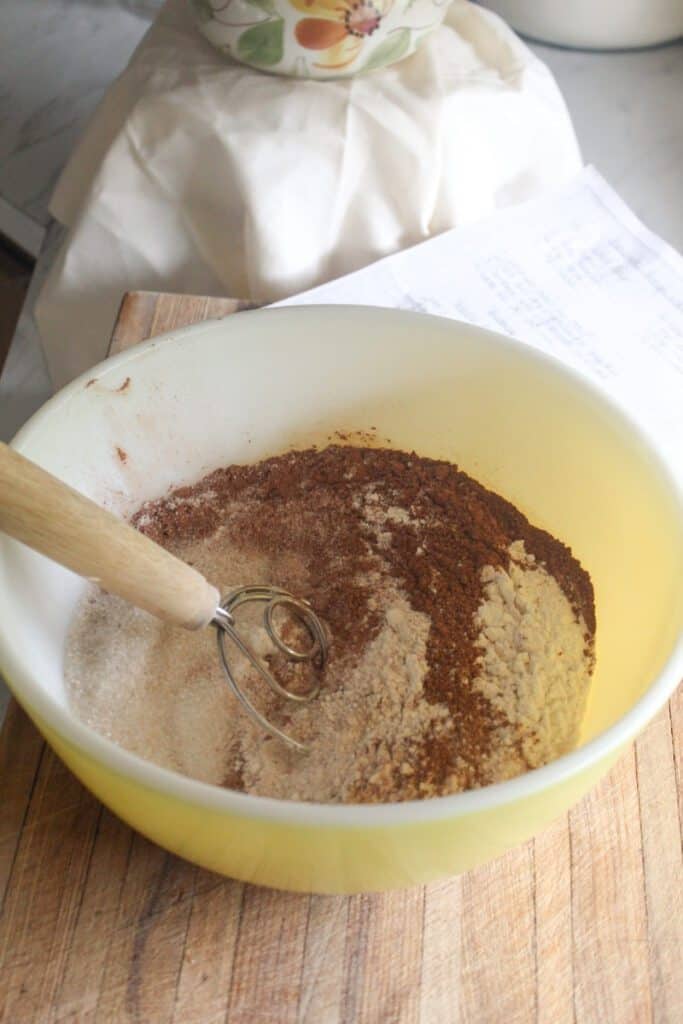 A bowl of mixed dry ingredients, including flour and cocoa powder, for a homemade chocolate cake.