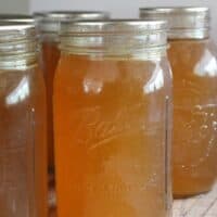 Homemade bone broth cooling in mason jars on a wooden surface
