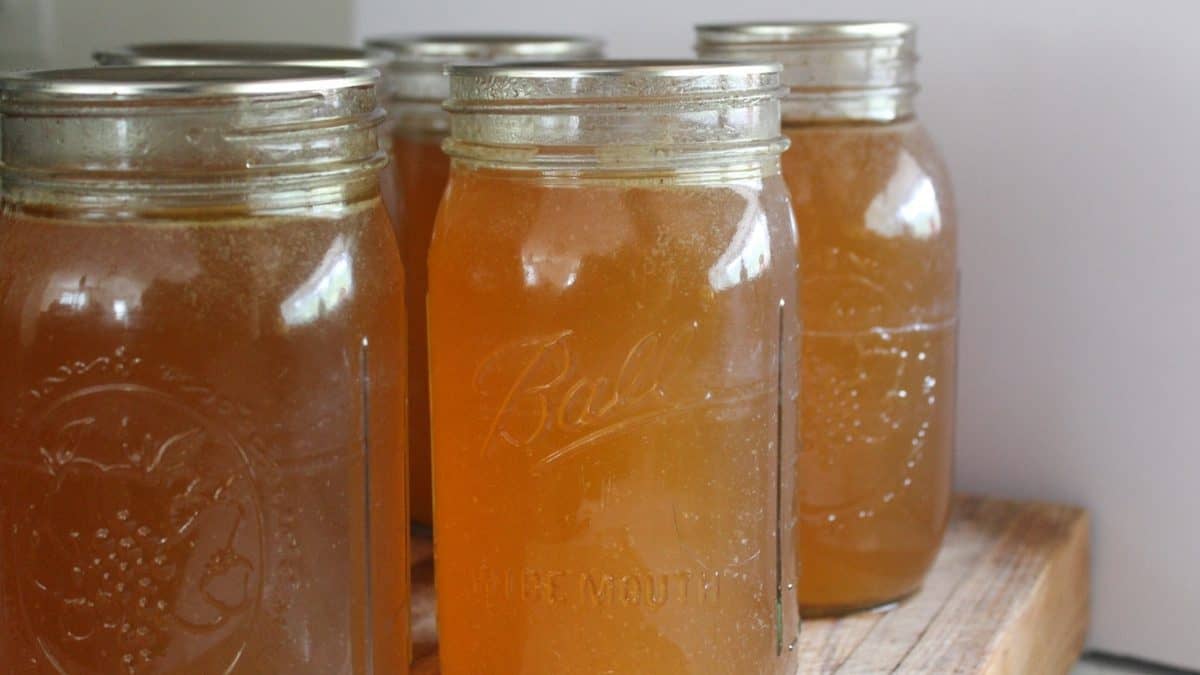 Homemade bone broth cooling in mason jars on a wooden surface