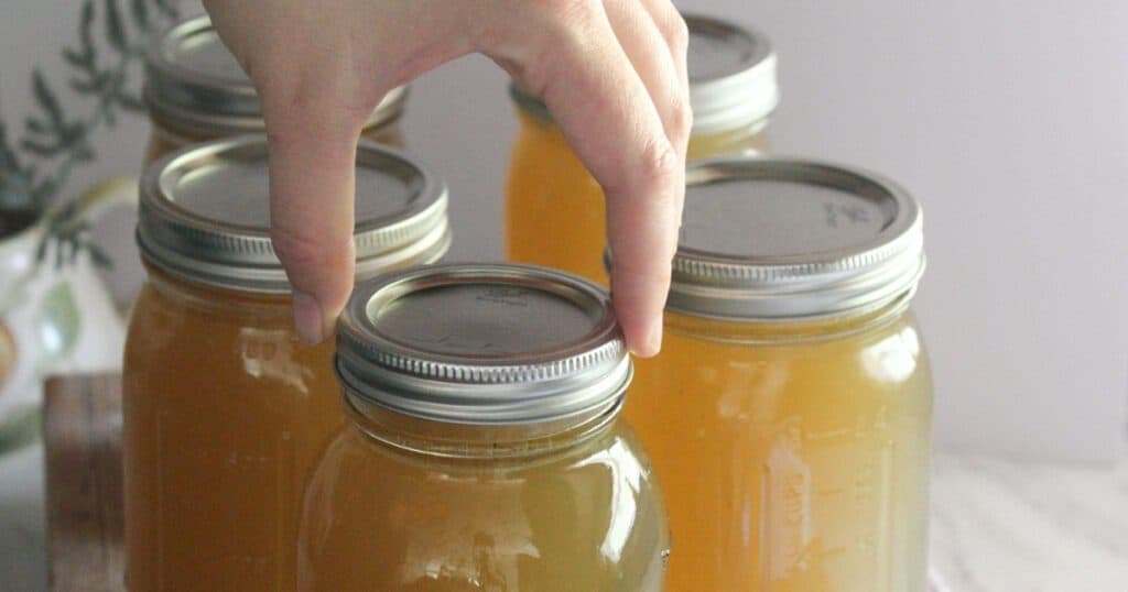 A close-up of a mason jar filled with golden homemade chicken bone broth.