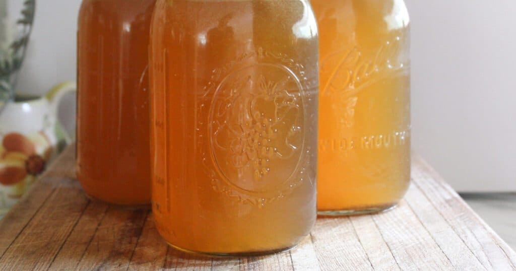 Sealed mason jars of bone broth arranged on a wooden table