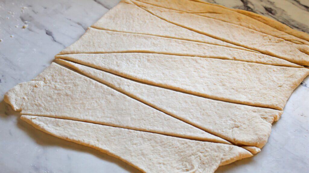 Cutting rolled sourdough dough into wedges with a pizza cutter