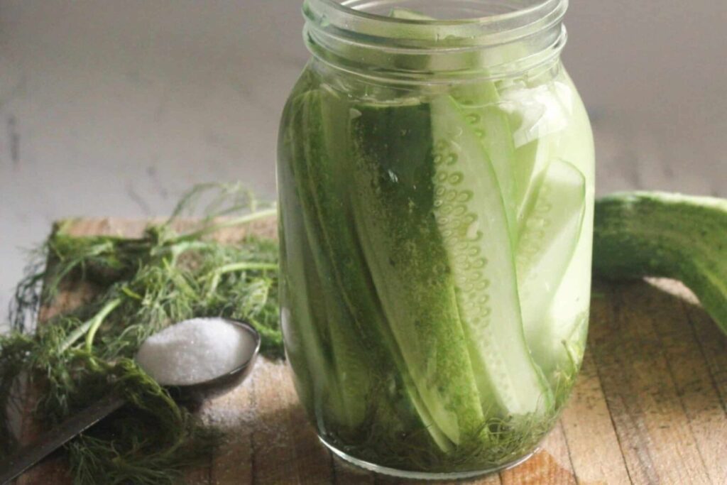Jar of homemade fermented dill pickles with garlic and fresh dill on a kitchen counter