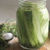 Jar of homemade fermented dill pickles with garlic and fresh dill on a kitchen counter