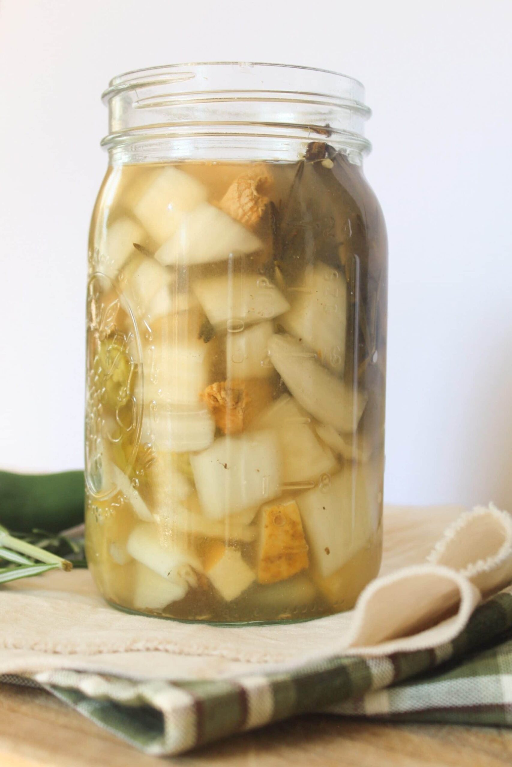 Fire Cider Recipe Detailed view of homemade fire cider recipe ingredients in a glass jar.