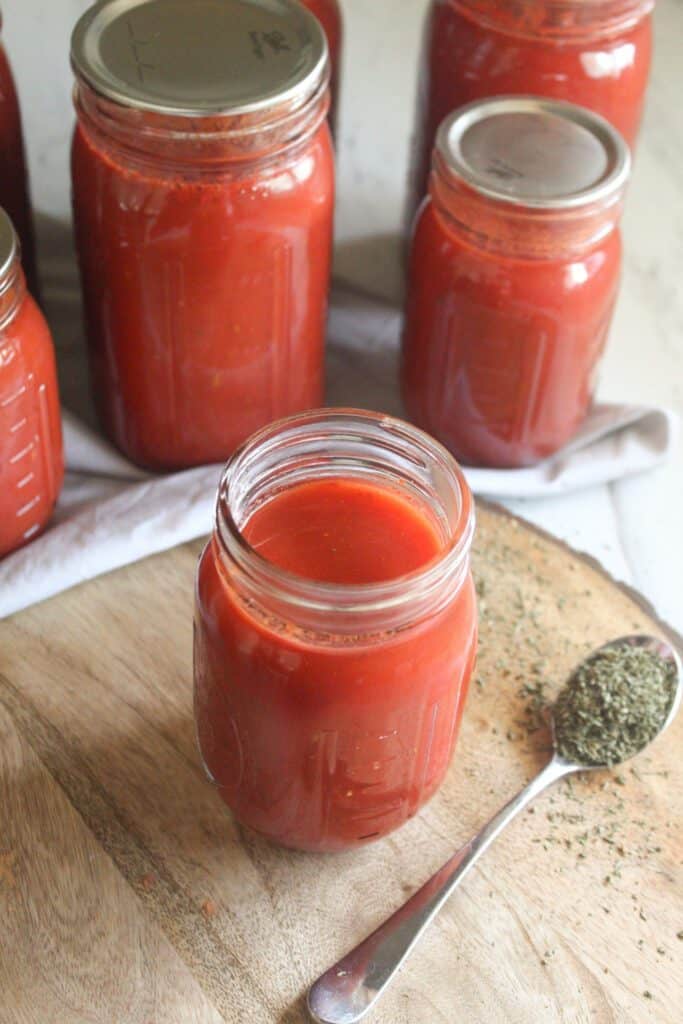 Jar of homemade tomato sauce in a glass jar on a wooden surface