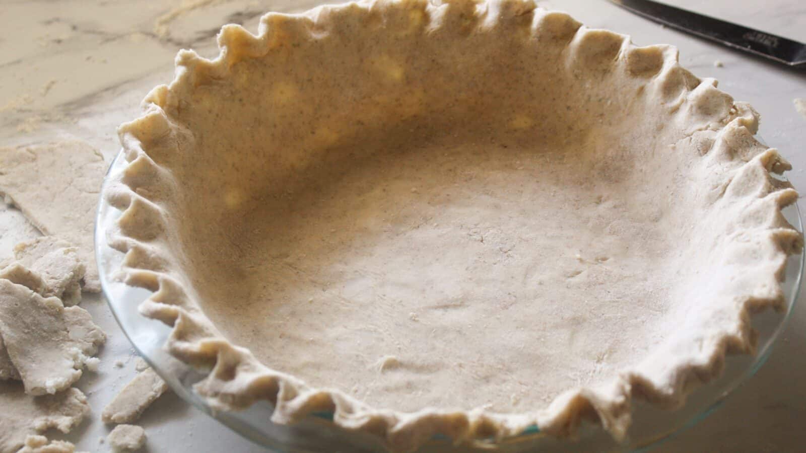Raw lard pie crust fitted in a pie pan, ready to bake