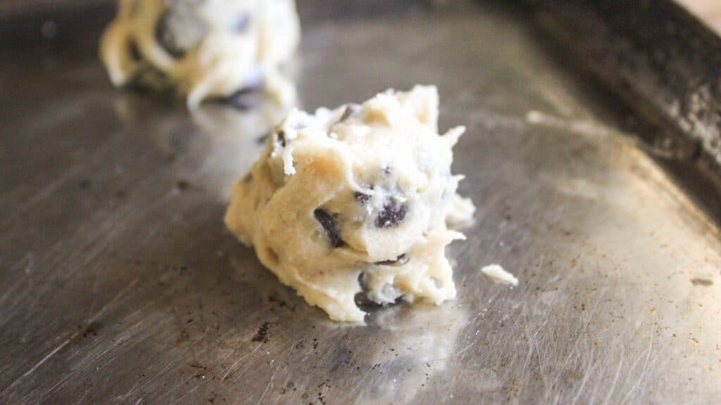 Scoop of vintage chocolate chip cookie dough on a baking sheet before baking.