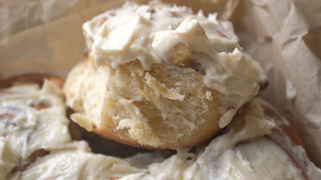 Apple Pie Cinnamon Rolls Close-up of a frosted apple cinnamon roll showing fluffy brioche texture.