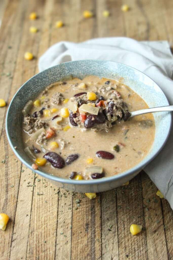Bowl of creamy taco soup with beans, corn, onions, and ground beef.
