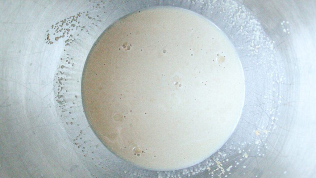 Yeast mixture bubbling in a mixing bowl.