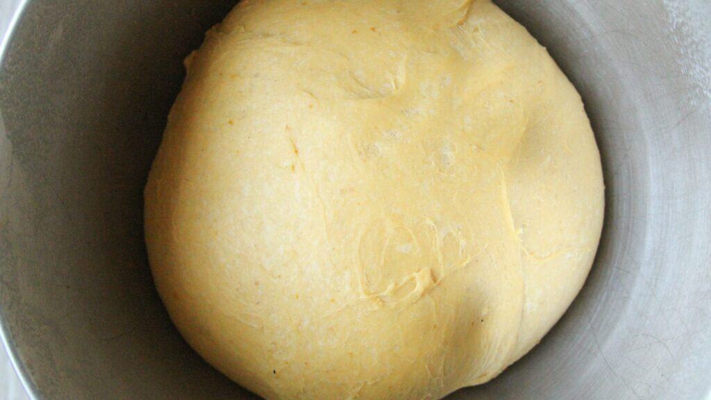 Pumpkin dough rising in a mixing bowl.