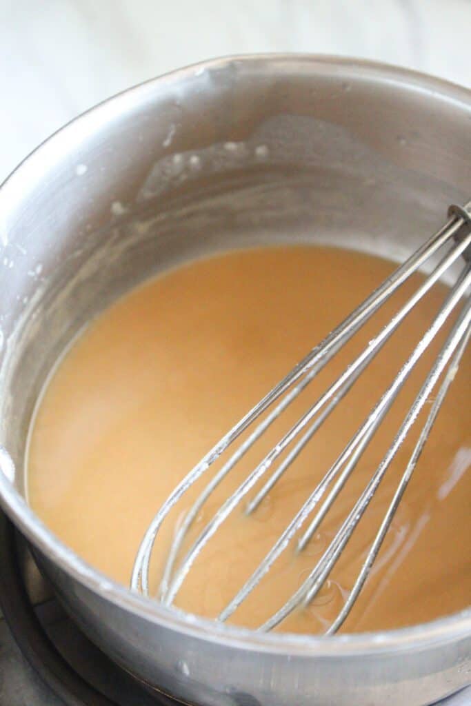 Bone Broth Gravy Thickened bone broth gravy in a saucepan with a whisk.