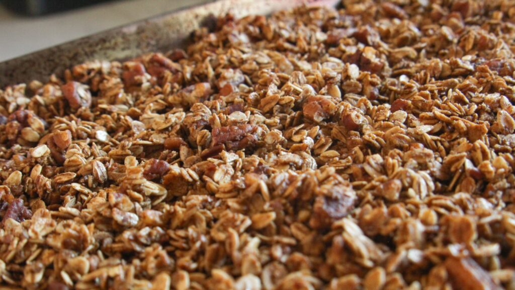 Crunchy pecan pie granola clusters cooling on a baking sheet.