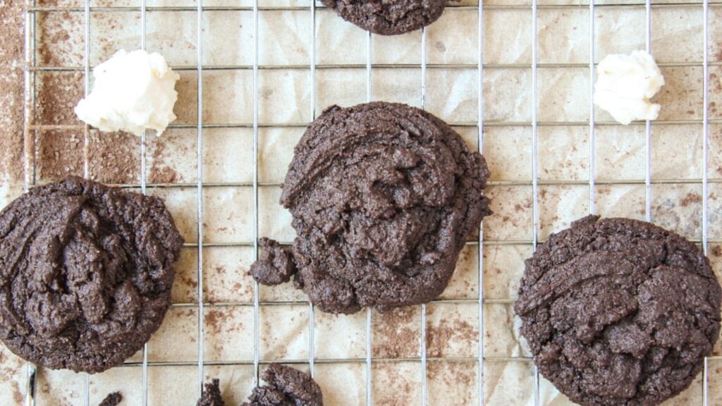 Chocolate peppermint cookies on a cooling rack topped with dollops of homemade marshmallow.
