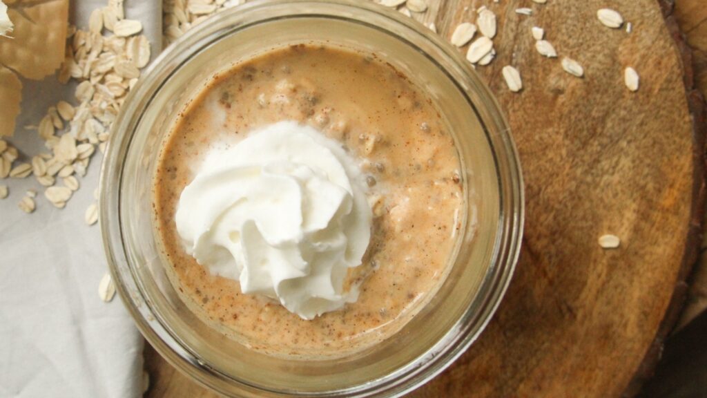 Pumpkin overnight oats jar on a wooden table with autumn decor