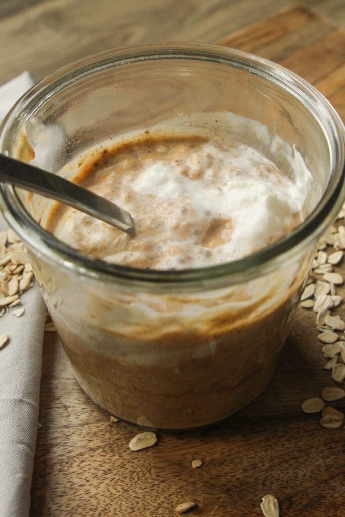 Top view of creamy pumpkin overnight oats in a jar, garnished with pumpkin seeds and cinnamon