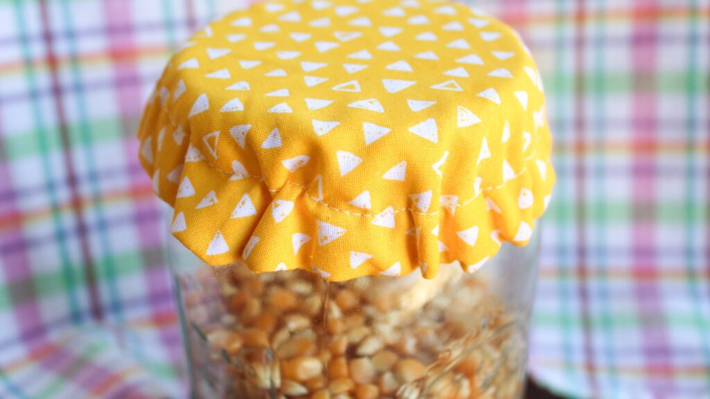 Sewn fabric mason jar covers with yellow polka dots.
