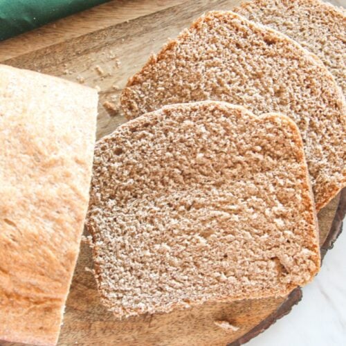 Half loaf of whole wheat bread with slices laying down