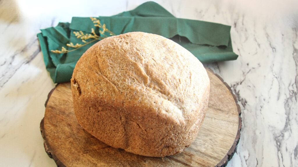 100% whole wheat bread machine loaf showing a golden brown crust and high rise.