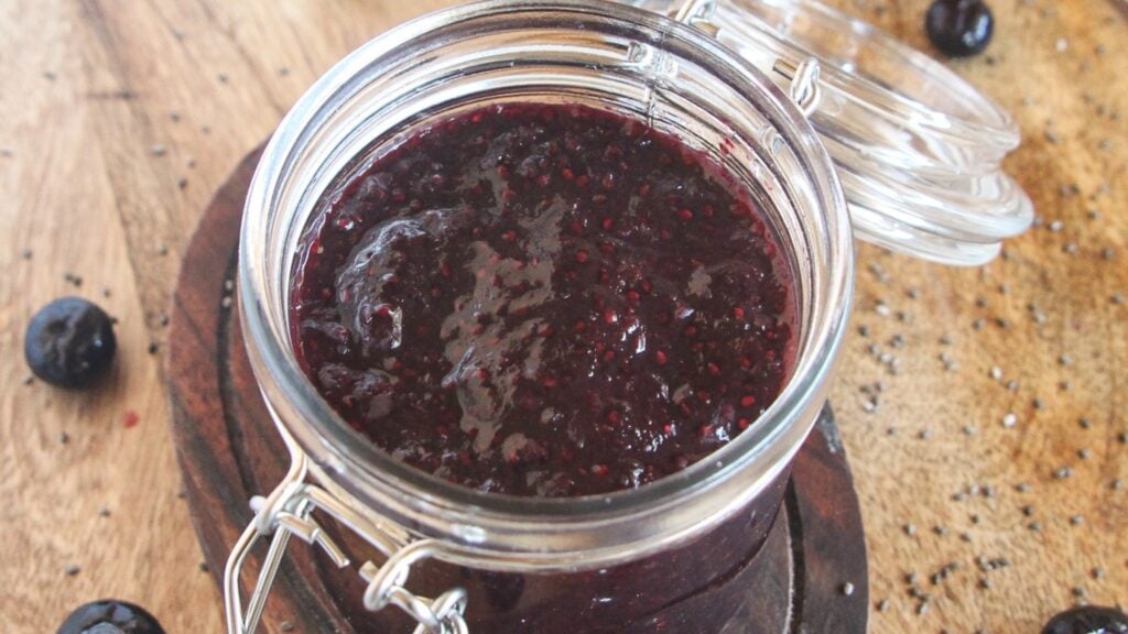 Easy 5-ingredient blueberry chia jam in a glass jar on a wooden board