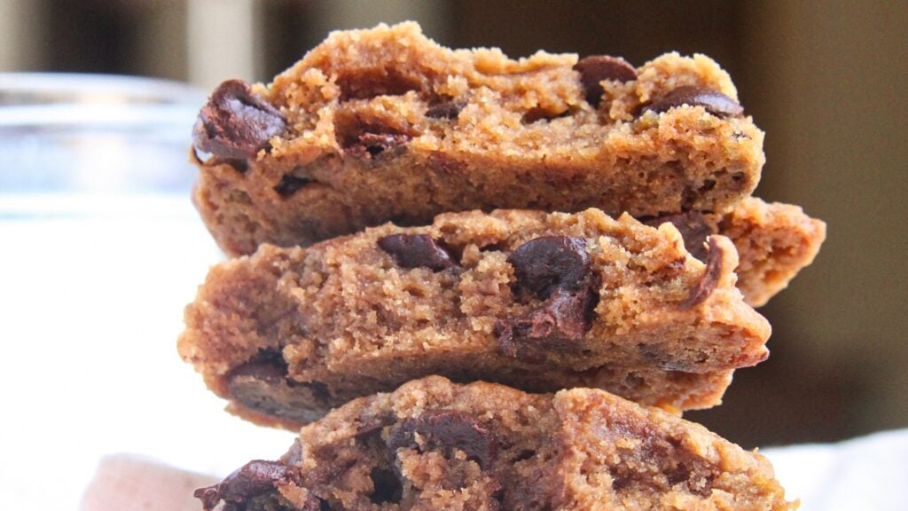 A close-up cross-section of a broken chocolate chip cookie showing a soft, fudgy center and melted chocolate.